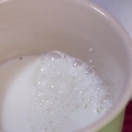 Skum melk for hånd for en cappuccino