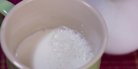 Skum melk for hånd for en cappuccino